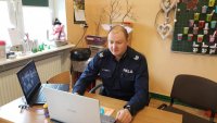 umundurowany policjant prowadzi prelekcję on-line przed komputerem