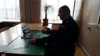 umundurowany policjant przed komputerem prowadzi prelekcję on-line
