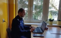 funkcjonariusz zespołu do spraw nieletnich i patologii w mundurze przed komputerem prowadzi prelekcję on line dla uczniów zespołu szkół ponadgimnazjalnych w Brzezinach