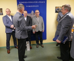 Komendant inspektor Marcin Grzelak wręcza szablę jednemu z odchodzących na emeryturę funkcjonariuszowi.