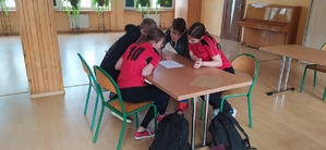 grupa uczniów rozwiązuje test siedząc przy stoliku.