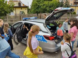 dzieci oglądają wnętrze policyjnego radiowozu.