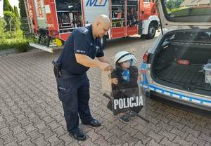 dzieci przymierzają strój policjanta zabezpieczającego imprezy masowe.