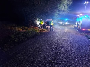 samochód na dachu, a przy nim policjanci i radiowóz.