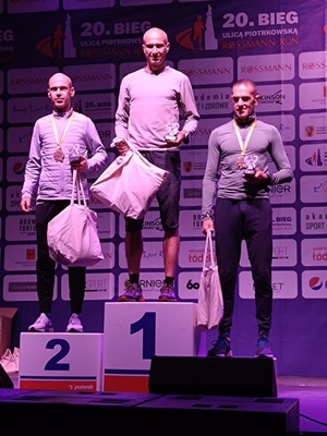 zawodnicy, który zajęli trzy pierwsze miejsca w biegu ulicą Piotrkowską Rossman Run stojący na podium.
