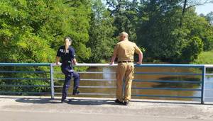 umundurowany policjant i umundurowany strażak kontrolują zbiorniki wodne.