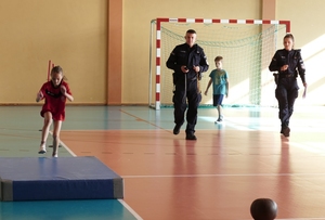 dziecko pokonujące tor przeszkód, a umundurowany policjant sprawdza poprawność i mierzy czas.