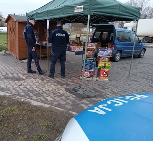 umundurowany policjanci kontrolują stoisko z fajerwerkami.