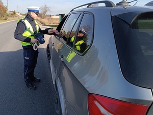 umundurowany policjant wręcza kierującym zapachowe serduszka.