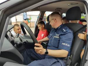 uczestnicy pikniku oglądają policyjny oznakowany radiowóz.