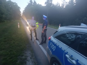 umundurowany policjant wręcza elementy odblaskowe.