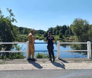 umundurowany policjant wraz z umundurowanym strażakiem kontrolują zbiorniki wodne.