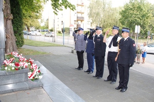 umundurowani policjanci składają kwiaty przed pomnikiem i oddają hołd.