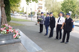 umundurowani policjanci składają kwiaty przed pomnikiem i oddają hołd.