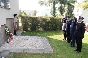 umundurowani policjanci składają kwiaty przed pomnikiem i oddają hołd.