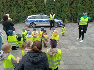 umundurowany policjant rozdaje dzieciom elementy odblaskowe.