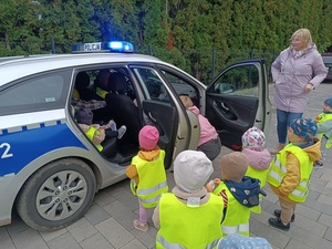 dzieci oglądają wnętrze oznakowanego radiowozu.