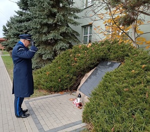 Komendant w galowym mundurze oddaje hołd pomordowanym policjantom.