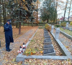 Komendant w galowym mundurze oddaje hołd pomordowanym policjantom.