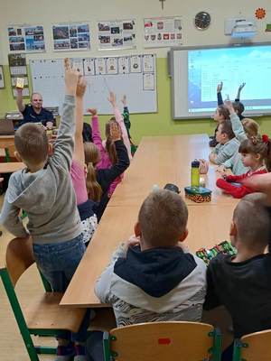 dzieci słuchają prelekcji prowadzonej przez umundurowanego policjanta.