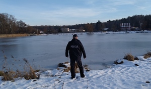 umundurowany policjant stoi nad wodą.