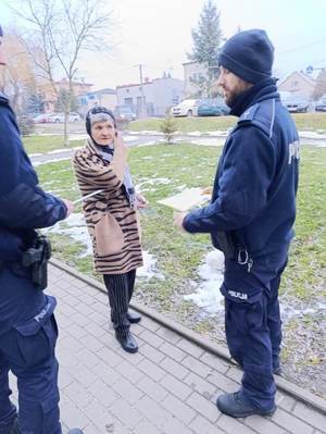 umundurowany policjant wręcza elementy odblaskowe napotkanemu seniorowi.