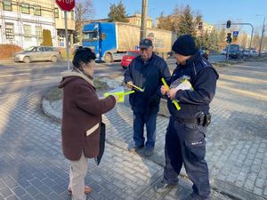 umundurowany policjant wręcza elementy odblaskowe.