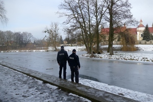 umundurowani policjanci kontrolują zamarznięte zbiorniki wodne.