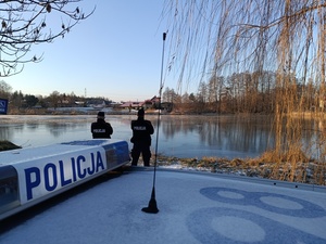 umundurowani policjanci kontrolują zamarznięte zbiorniki wodne.