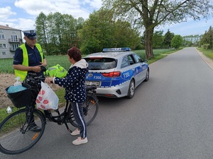umundurowany policjant ruchu drogowego wręcza kamizelkę odblaskową niechronionemu uczestnikowi ruchu drogowego.