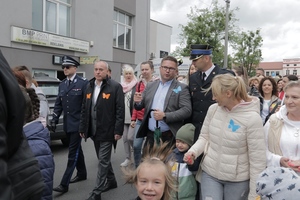komendant w mundurze galowym idzie wraz z innymi uczestnikami przemarszu.