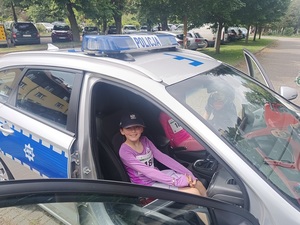 dziewczynka siedząca w oznakowanym radiowozie.