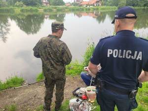 umundurowany policjant wspólnie z funkcjonariuszem straży  rybackiej prowadzą kontrole  akwenów wodnych.