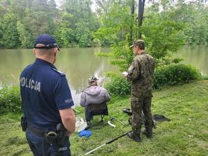 umundurowany policjant wspólnie z funkcjonariuszem straży  rybackiej prowadzą kontrole  akwenów wodnych.