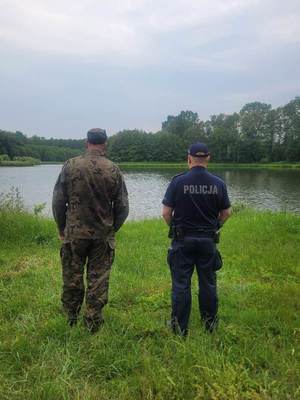 umundurowany policjant wspólnie z funkcjonariuszem straży  rybackiej prowadzą kontrole  akwenów wodnych.
