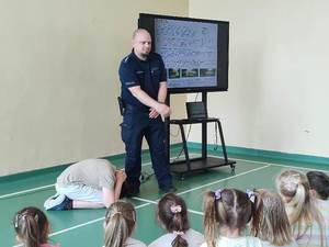 uczniowie słuchają prelekcji prowadzonej przez umundurowanego policjanta.