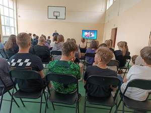 uczniowie słuchają prelekcji prowadzonej przez umundurowanego policjanta.