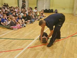 dzieci słuchają prelekcji prowadzonej przez umundurowanego policjanta.