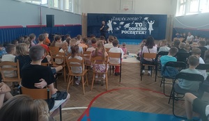 dzieci słuchają prelekcji prowadzonej przez umundurowanego policjanta.