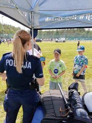 osoby odwiedzające policyjne stoisko, gdzie znajdują się umundurowani policjanci.