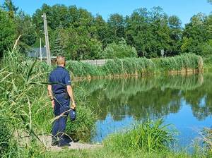 umundurowany policjant kontroluje akwen wodny.