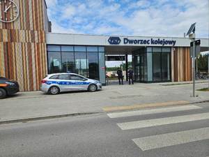 umundurowany policjant i strażnik ochrony kolei stoją na peronie stacji kolejowej.