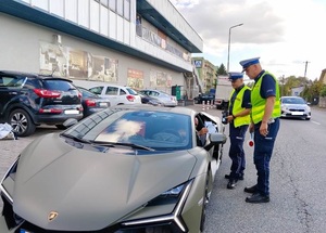 umundurowany policjanci podczas kontroli drogowej wręczają materiały promocyjne kampanii.