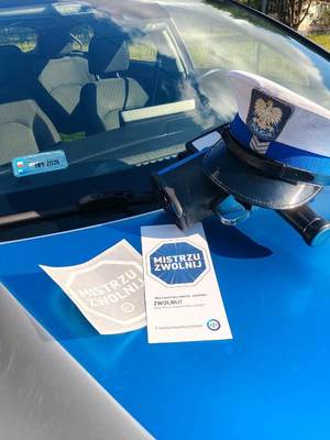 umundurowany policjanci podczas kontroli drogowej wręczają materiały promocyjne kampanii.