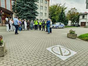 wszyscy uczestnicy przedsięwzięcia stoją w tle przed piktogramem.