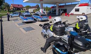 umundurowani policjanci i oznakowane radiowozy stoją w miejscu, gdzie odnaleziono poszukiwanego mężczyznę.