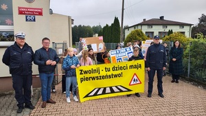 wszyscy uczestniczący w montowaniu banneru stoją na tle szkoły.