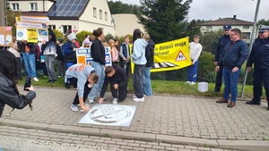 dzieci z bannerem stoją przy przejściu dla pieszych.