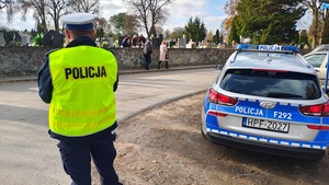umundurowany policjant ruchu drogowego stoi na wjeździe do cmentarza.