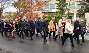 uczestnicy uroczystości w asyście policji idą ulicami miasta.